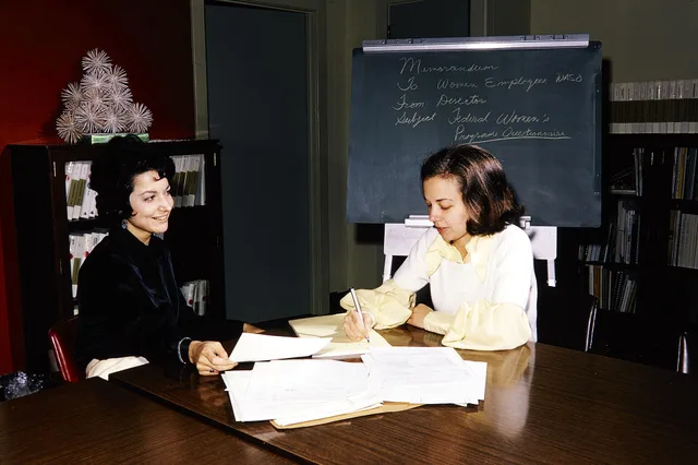 NPS employees looking through paperwork in the Womens Program in Washington Office. Keywords: nps staff; desk; NPS Personnel(NPS History Collection Themes); Women(NPS History Collection Themes); Communications(NPS History Collection Themes). Proposal software licence terms to check before buying