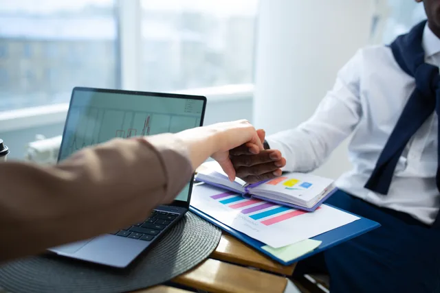 Two business professionals shaking hands over graphs and reports in an office setting. A proposal software launch review should separate claims from evidence